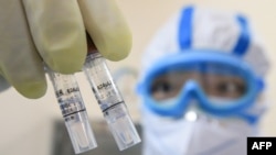 Një punëtor në një laborator në Kinë mban në duar mostrat e koronavirusit të ri, të emëruar COVID-19.