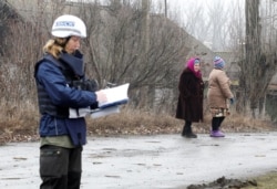 A monitor from the OSCE works in the settlement of Holubivske in the Luhansk region that has been affected by fighting.