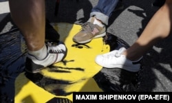 Russians stomp on a portrait of Putin at a rally against increases in the pension age in Moscow on July 29.