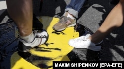 Russian opposition activists show their displeasure by stepping upon a portrait of Russian President Vladimir Putin at a rally in Moscow on July 18 against proposed retirement-age increases.