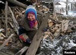 A woman reacts as she removes debris in front of her house, which was damaged during fighting between pro-Russian rebels and Ukrainian government forces, in the town of Horlivka, in eastern Ukraine, on February 10.