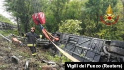 A firefighter stands next to an overturned tourist bus that crashed in Italy's Tuscany region on May 22.