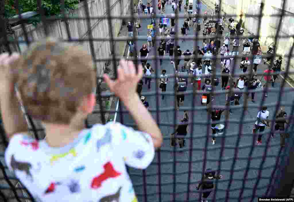 A young boy looks on as demonstrators march down a road to a highway, as protests triggered by the death of George Floyd while in police custody, continue on June 23, 2020, in Washington, DC. -