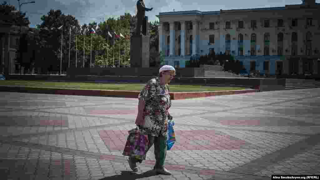 Женщина идет с покупками по площади Ленина 