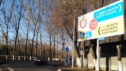 Жемқорлықпен күресуге шақырған жарнама жанында тұрған ішкі істер әскери қызметкерлері. Алматы, 21 наурыз 2015 жыл.