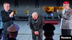 Cancelarul german în funcție, Olaf Scholz (centru), se închină la o ceremonie militară (Grosser Zapfenstreich) pe 5 mai, luându-și rămas bun la final de mandat, find aplaudat de ministrul Apărării, Boris Pistorius (stânga) și inspectorul general al armatei, Carsten Breuer.