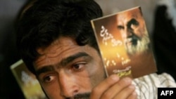 A man in 2007 holds a portrait of Ayatollah Ruhollah Khomeini during a memorial ceremony to mark the 18th anniversary of Khomeini's death at his mausoleum in Tehran.