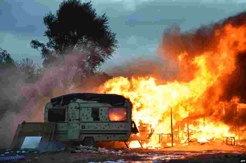 A photo taken early on October 28 shows a burning trailer at the &quot;Jungle&quot; migrant camp in Calais, France, following a massive operation to clear the settlement where 6,000-8,000 people had been living. (AFP/Philippe Huguen)