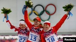 Belarusians gold medalist Darya Domracheva (center) and bronze medalist Nadezhda Skardino (right) celebrate during the flower ceremony for the women's biathlon 15-kilometer individual event at the 2014 Sochi Winter Olympics on February 14.