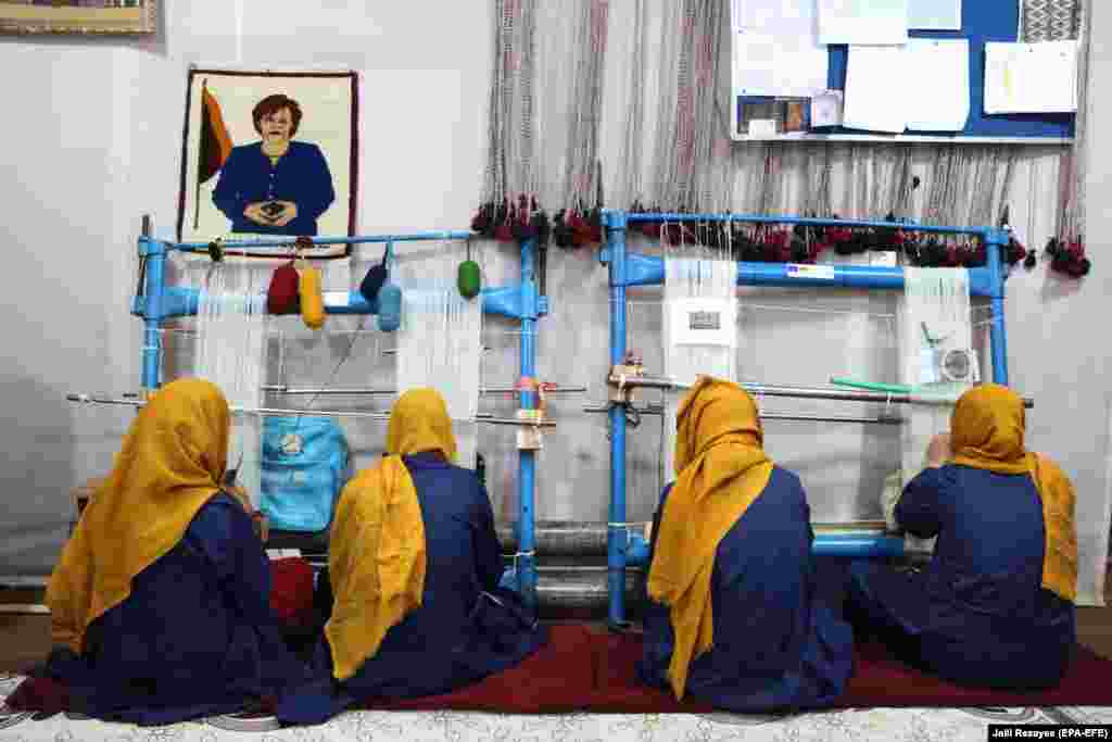 A handwoven image of German Chanceller Angela Merkel hangs on a wall as Afghan women attend a carpet-weaving class as part of vocational training in Herat, Afghanistan. (epa-EFE/Jalil Rezayee)