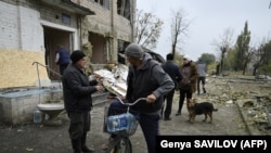 Локалните жители зборуваат додека застануваат пред локалната административна зграда, уништена по штрајкот во селото Шевченко, во регионот Доњецк, на 20 октомври 2024 година