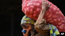 <p>A laborer carries a sack of potatoes at a wholesale vegetable market in Islamabad, Pakistan. 
