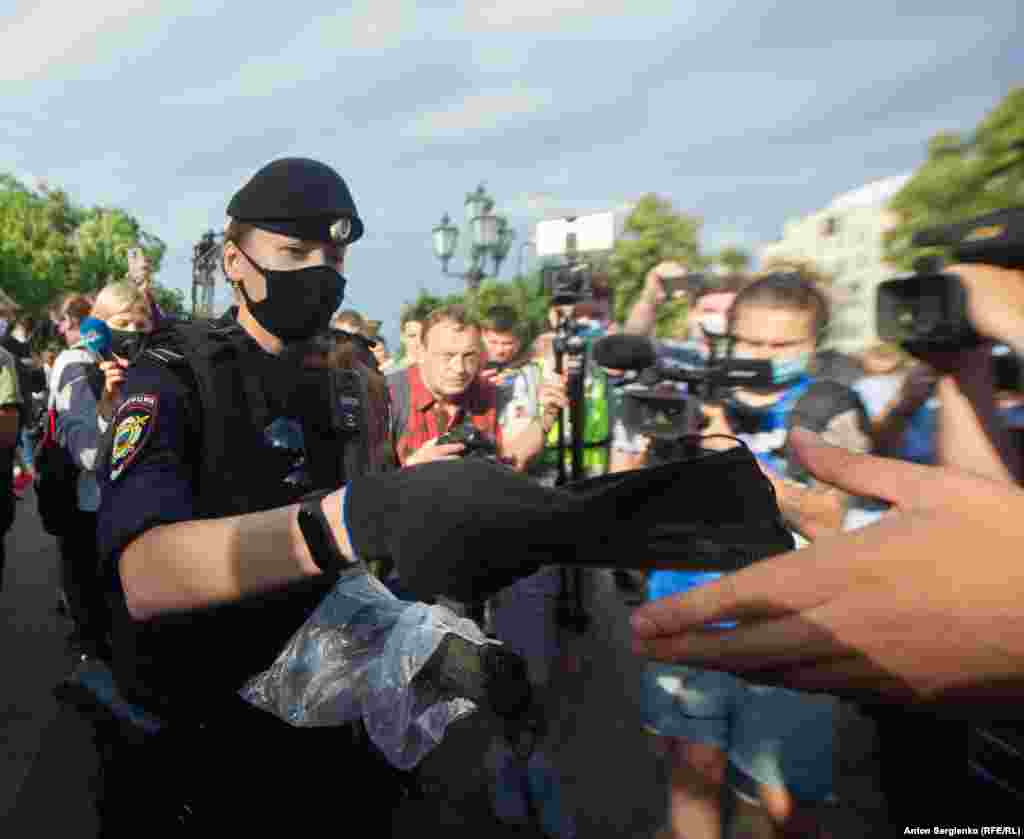 Полиция раздает протестующим черные маски.