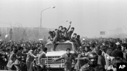 IRAN -- Ayatollah Khomeini Return from Exile 1979 -- Excited followers of the Ayatollah Khomeini, behind windshield, left, throng his motorcade as he leaves the airport for Behesht Zahra Cemetery, in Tehran, Iran, Feb. 1, 1979.