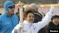 Ольга Шишигина бежит с пламенем зимних Азиатских игр во время эстафеты олимпийского огня в Алматы. 12 января 2011 года