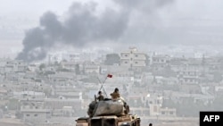 Турецкие военные наблюдают за происходящим в приграничном сирийском городе Кобани. 