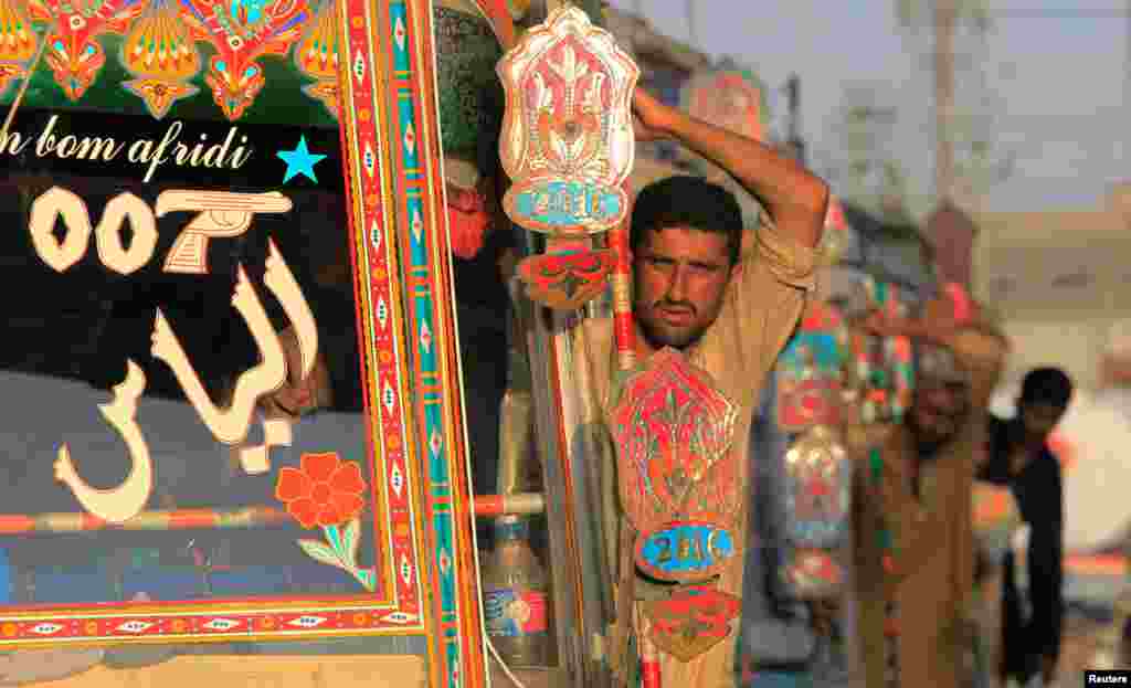 Pakistan, Karaçi, ýol hereketiniň gyzan wagty. Awtobus gullukçylary ýolagçylara seredýärler. (Reuters/Caren Firouz)