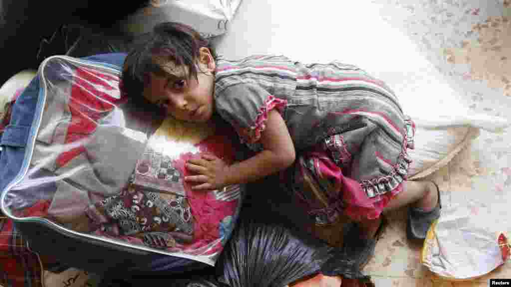 A Syrian girl lies on top of luggage at a makeshift refugee camp inside Iraq after crossing the Iraqi-Syrian border at Albu Kamal-Qaim, the main border post between the two countries, on July 24. (REUTERS/Saad Shalash)