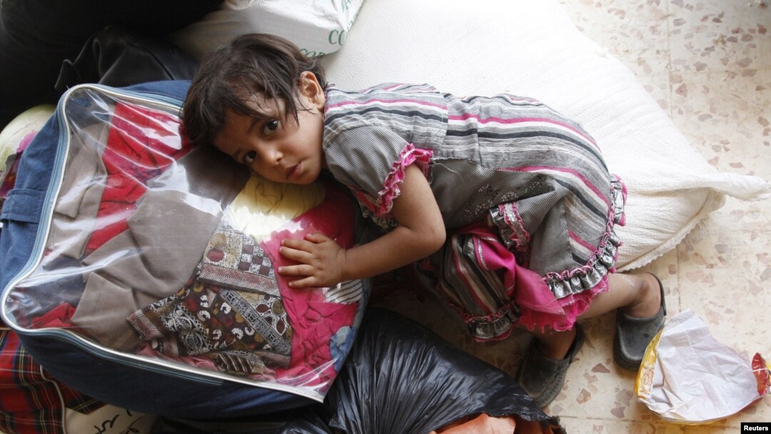 A Syrian girl lies on top of luggage at a makeshift refugee camp inside Iraq after crossing the Iraqi-Syrian border at Abu Kamal-Qaim, the main border post between the two countries, on July 24.