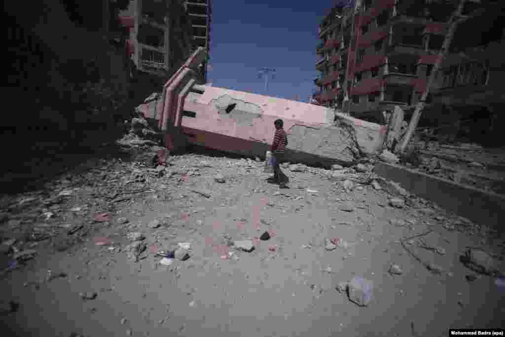 A Syrian boy walks past the collapsed minaret of a mosque in the rebel-held city of Douma, outside Damascus, on March 31. (epa/Mohammed Badra)