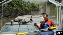 A man and his son kayak past flooded cars in Bundaberg, Australia, on December 31.
