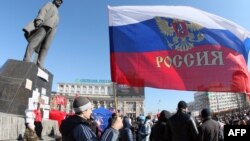 Ukraine -- A pro-Russian protester waves a Russian flag next to a statue of Vladimir Lenin during a rally in the centre of the eastern city of Donetsk, March 10, 2014