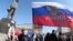 Ukraine -- A pro-Russian protester waves a Russian flag next to a statue of Vladimir Lenin during a rally in the centre of the eastern city of Donetsk, March 10, 2014
