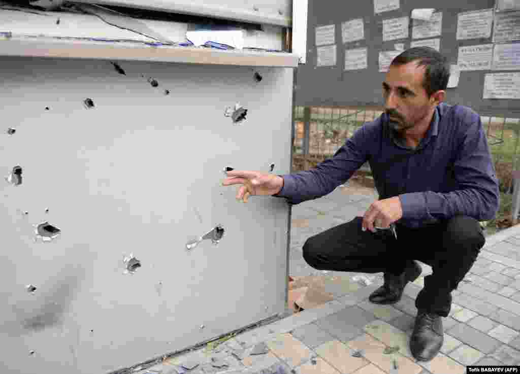 A man points at a kiosk in the Azerbaijani city of Tartar believed to have been damaged in the recent shelling.