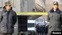 Kyrgyz policemen stand guard as security personnel work on the site of a blast in Bishkek on November 30, 2010. Authorities blamed it on a previously unknown group.