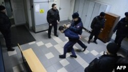 Полицейский ведет подозреваемого в связи со взрывом в петербуржском метро в здании суда в Санкт-Петербурге, 7 апреля, 2017 года