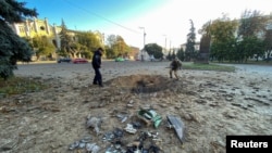 Policajci pregledavaju krater u kojem je dio presretnute ruske rakete, usred ruskog napada na Ukrajinu, u Harkivu, Ukrajina, 8. oktobra 2022. 