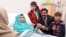 Malala Yousafzai, who was shot in the head by Taliban gunmen for campaigning for the right to an education, sitting on her bed amid her mother Toorpekai Yousufzai (L), brothers Khushal Khan (3rd R) and Apal Khan (R) and father