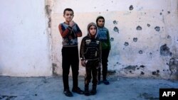 Boys watch as demining experts from the Iraqi Army search for booby-trapped buildings in eastern Mosul on January 17.