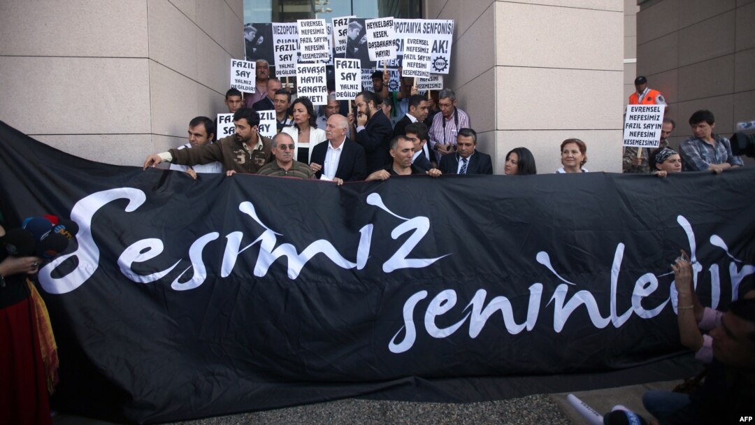 Supporters of world-renowned Turkish pianist Fazil Say stand behind a banner reading "Our voice is with you" during a protest held outside an Istanbul court, on October 18.
