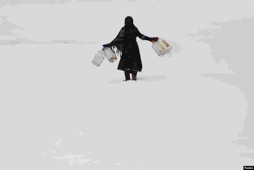 An Afghan girl carries empty water containers during a snowfall in Kabul on February 6. (Reuters/Mohammad Ismail)