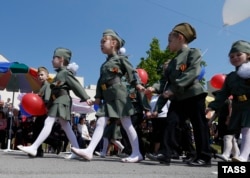 Disa fëmijë duke marrë pjesë në një marsh të titulluar "Parada e fëmijëve", e cila mbahet për të shënuar fitoren e Rusisë ndaj Gjermaninë naziste.