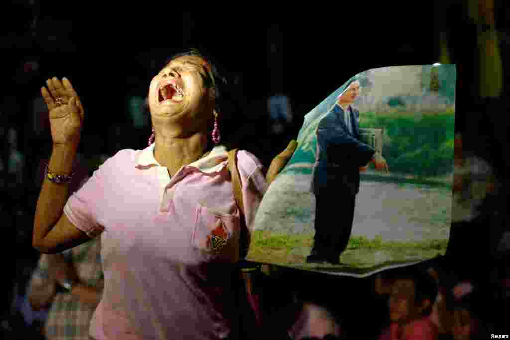 Bangkok, Taýlandyň 13-nji oktýabrda ýogalan patyşasy Bhumibol Adulyadejiň portretini galdyryp, aglaýan aýal. (Reuters/Chaiwat Subprasom)