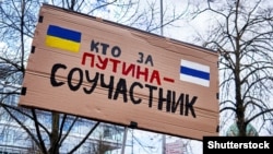 Плакат на русском языке «Кто за Путина – соучастник» на демонстрации против войны России в Украине, Ганновер, Германия, 9 апреля 2022 года