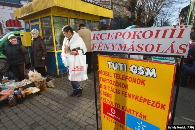 Місцеві жителі біля рекламного плаката угорською мовою в Берегові, 15 листопада 2017 року