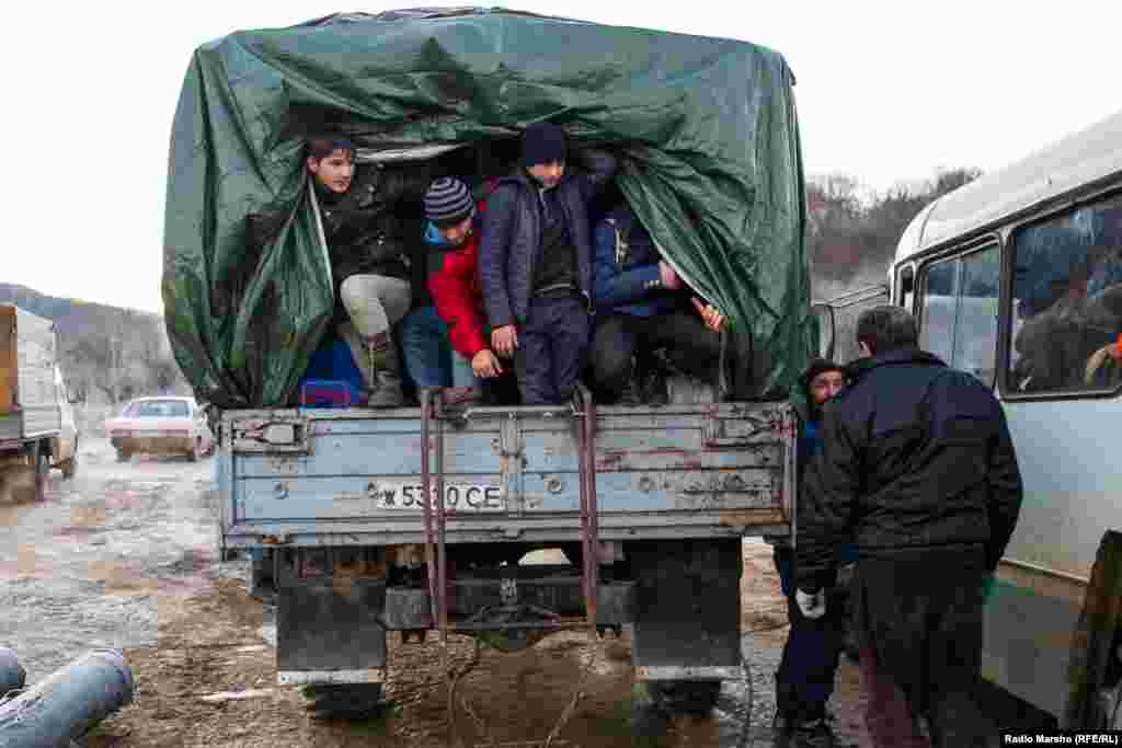 Pickers, many of them young boys, scramble into the back of a pickup truck for the journey across muddy, rutted pathways.