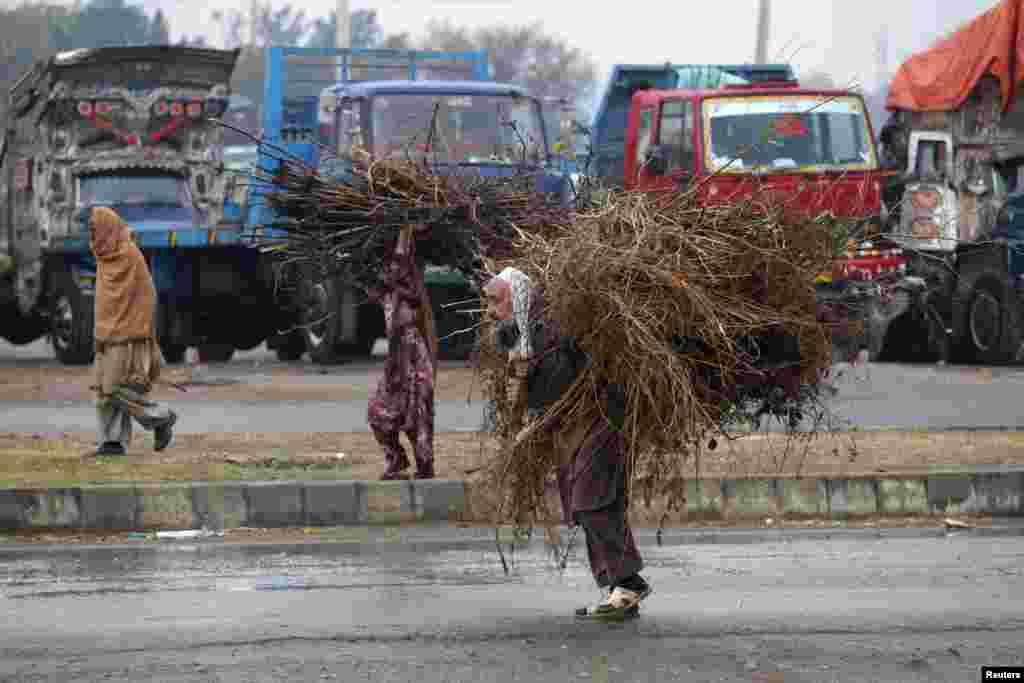 A Pakistani man and a woman carry tree branches, used as fuel for cooking, on the outskirts of Islamabad, on December 11. (Reuters/Mian Khursheed)