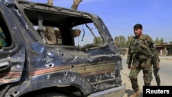 An Afghan National Army soldier inspects the wreckage of vehicles at the site of a suicide attack that targeted a NATO convoy in Jalalabad on April 10.