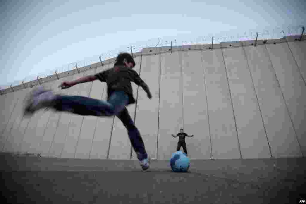 Palestinian children play football in front of the controversial Israeli separation barrier in the West Bank village of Abu Dis on the outskirts of Jerusalem. (AFP/Ahmad Gharabli)