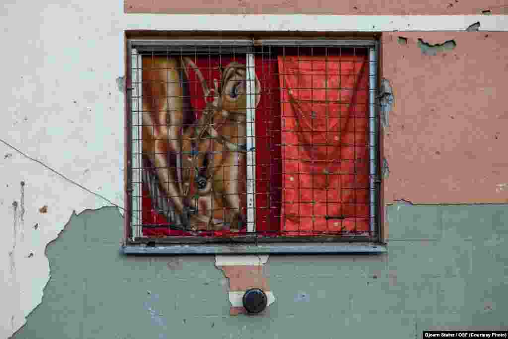 Most of the ground-floor windows at the housing complex are broken. Here, a window is covered with blankets.