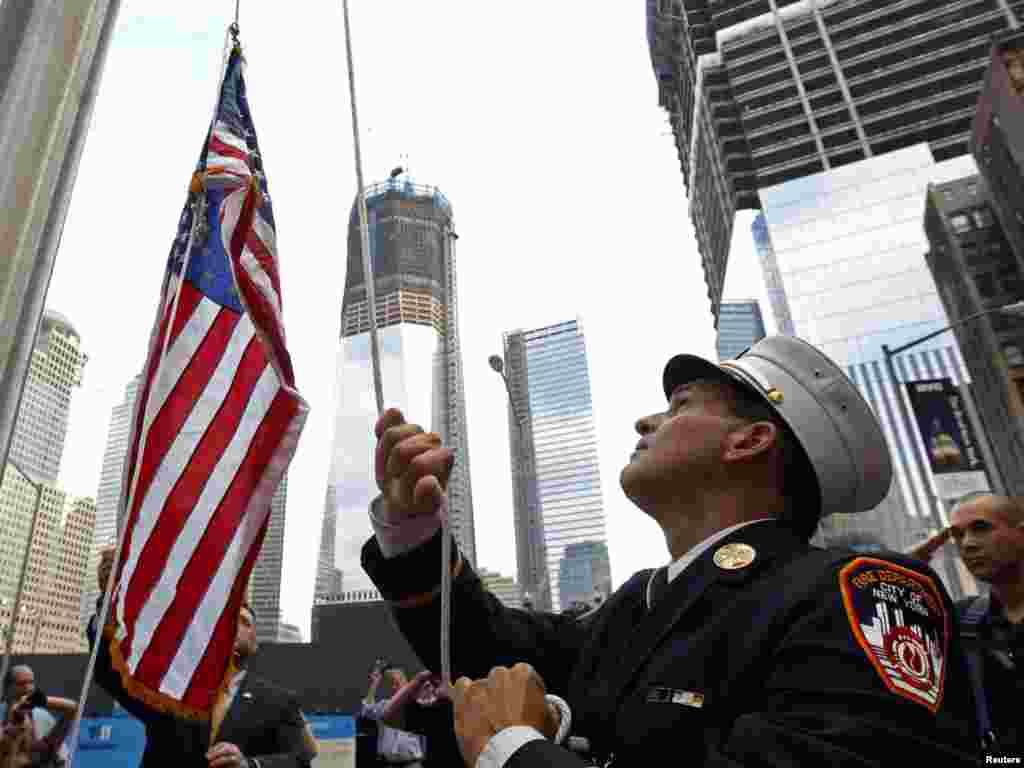 New York Fire Department Battalion Commander Tom Currao raises a flag outside the World Trade Center construction site at the 9/11 Memorial Visitors Center in New York on September 9. (Photo by Brian Snyder for Reuters)