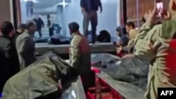 تصویری از یک ویدئو که پیکرهای در حال انتقال را جلوی یک یک کانیتنر حمل اجساد در محوطهٔ پزشکی قانونی کهریزک نشان می‌دهد