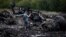 A journalist takes photographs at the site of the Malaysia Airlines Boeing 777 plane crash near the settlement of Hrabovo, in the Donetsk region, on July 18, one day after the crash, which killed all 298 people aboard.