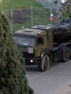 Un camion militar rusesc se apropie, pe 15 decembrie,&nbsp;de intrarea în baza aeriană Hmeimim, care se află la mică distanță de orașul Latakia, din vestul Siriei.<br />
<br />
Această fotografie este una din câteva făcute recent de Umit Bektas, un fotoreporter turc care lucrează pentru Reuters și care a relatat pentru Europa Liberă despre este situația din jurul bazei rusești.