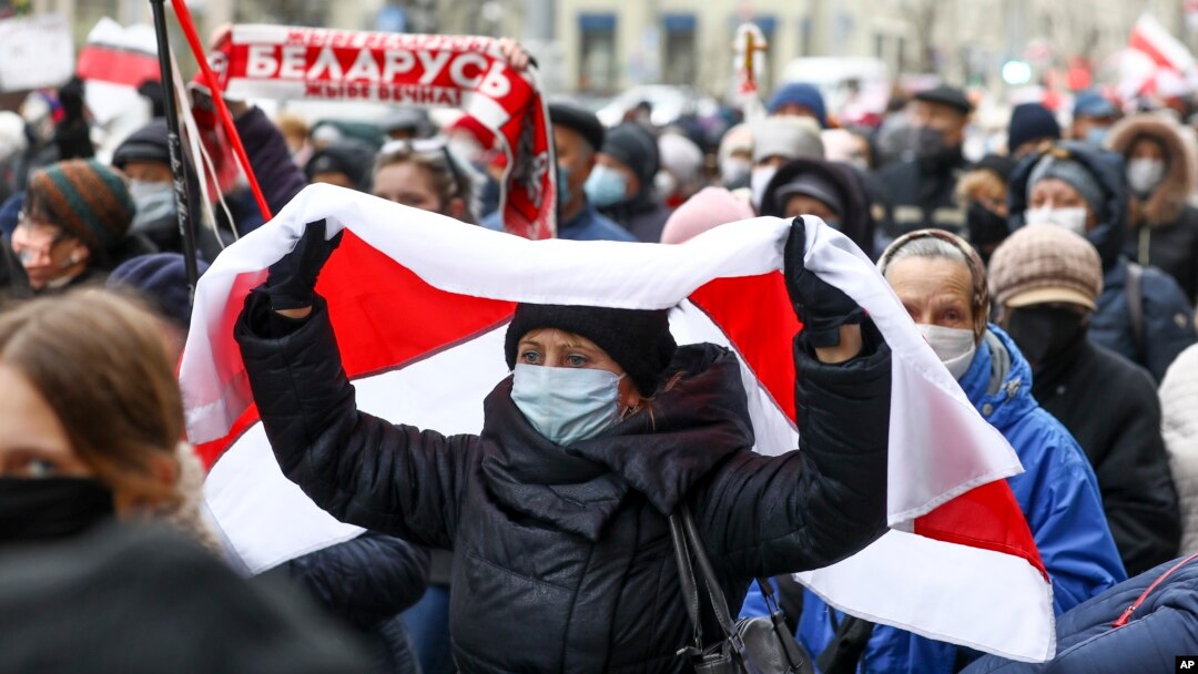 A woman covers herself with an old Belarusian national flag at a protest rally in Minsk in November 2020.