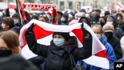 A woman covers herself with an old Belarusian national flag at a protest rally in Minsk in November 2020.